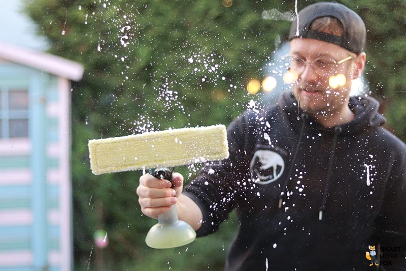 Man sieht wie ein Mann ein Fenster einseift und abwischt.
